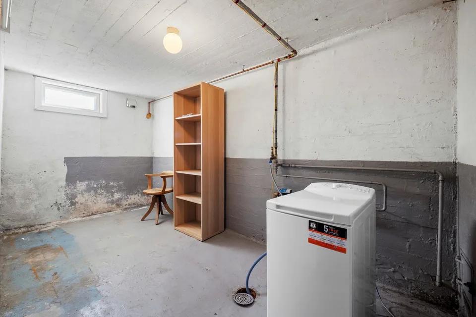 Unfinished basement room with exposed pipes before renovation