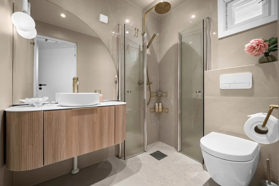 Renovated bathroom with glass shower screens and timber vanity