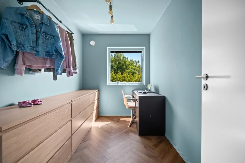 Blue room with herringbone flooring, drawers and a desk