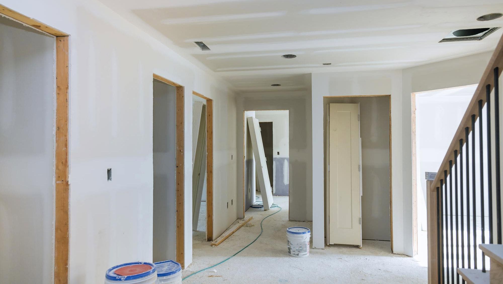 Bolig under oppussing med uferdige vegger, verktøy og materialer spredt på gulvet.